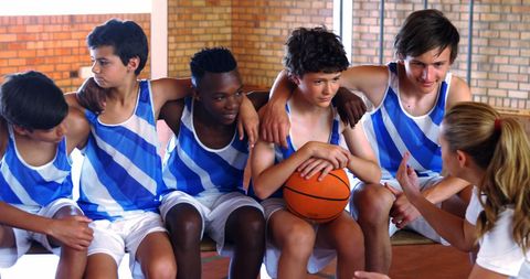 Diverse teen basketball players listening to coach in team huddle