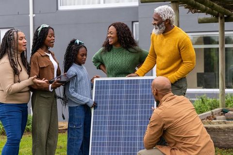 African american family installing solar panel with installer showing renewable energy benefits