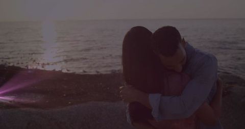 Couple Embracing by Ocean at Sunset Creates Romantic Scene