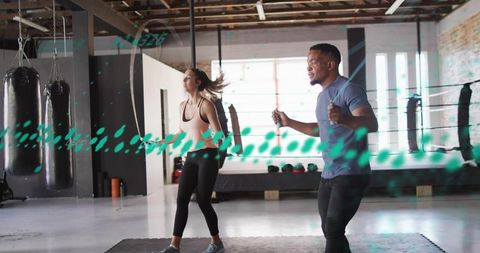 Partners skipping rope for high-intensity cardio and strength training in industrial gym studio