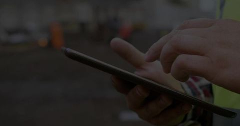 Closeup Mid-adult Construction Worker Tapping Tablet While Inspecting Jobsite