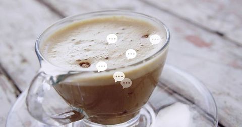 Rustic glass cup of frothy latte on weathered white table with soft natural light closeup