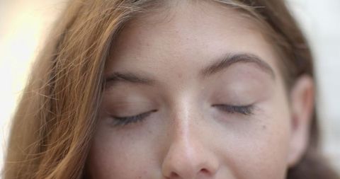 Relaxed Woman in Soft Light with Closed Eyes and Long Brown Hair