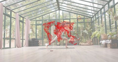 Woman practicing yoga lunge in glass greenhouse studio with lush plants and sunlight
