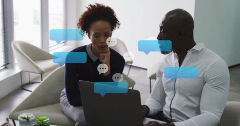 Collaborating over laptop in modern office lounge with digital chat overlays