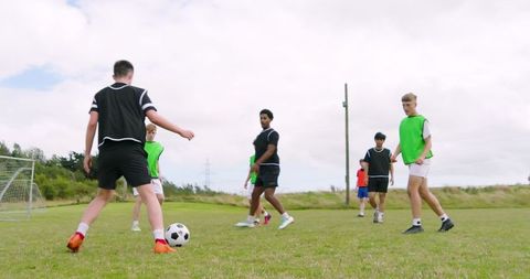 Teenagers playing soccer game on green field outdoors