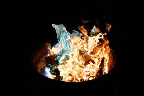 Multicolor Flames Burning in Metal Barrel at Night Blue and Orange Campfire Firelight