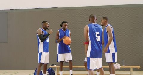 Basketball team huddling on indoor court in blue uniforms holding ball and planning plays