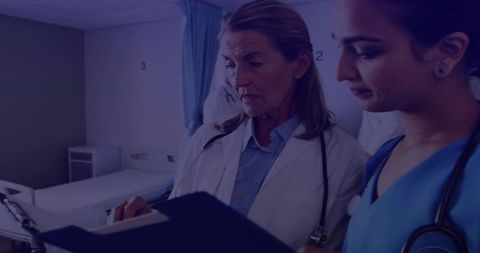 Female Doctor and Nurse Discussing Patient Chart Hospital Room