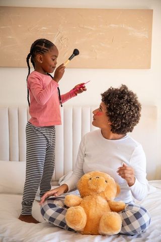 Diverse Mother and Daughter Playing Makeup in Bedroom