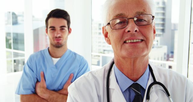 Senior doctor smiling with young medical professional in modern hospital. Perfect for use in healthcare, medical teamwork, mentorship promotions, hospital advertisements, senior health care experiences.