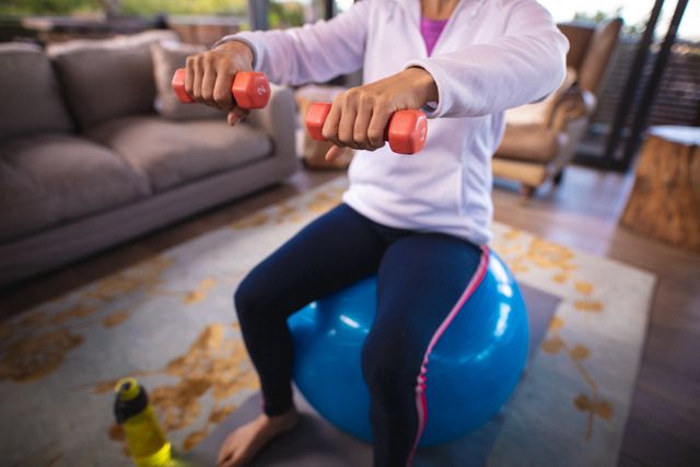 Portrait of smiling senior caucasian woman sitting on swiss ball, exercising with dumbbells - Download Free Stock Photos Pikwizard.com