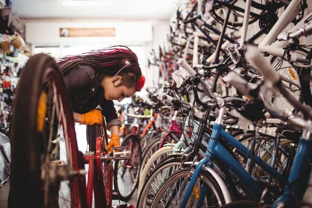 Female mechanic focused on repairing a bicycle in bike shop workshop. Suitable for illustrating bike maintenance, professional repair services, women in skilled trades, and cycling-related businesses.