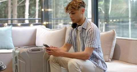 Young Traveler Relaxing with Smartphone in Stylish Lounge Area