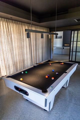 Modern white pool table with black felt and scattered balls in contemporary lounge