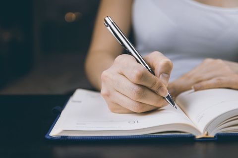 Closeup of Woman Writing in Journal at Desk