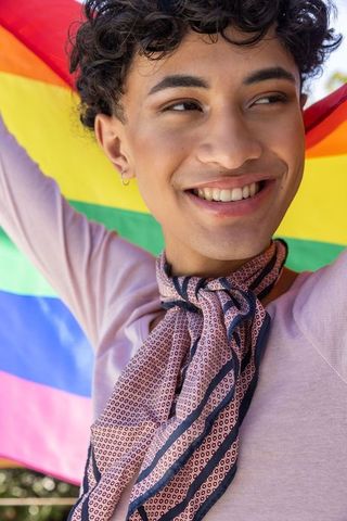 Joyful person celebrating with rainbow flag outdoors