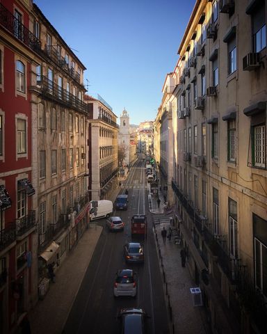 Sunlight Bathing Lisbon Hill Street with Tram Tracks Leading to White Church Tower