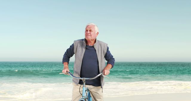Retired old man on bike pointing the sky on the beach