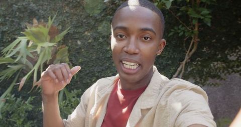 Young man creating content in lush backyard environment