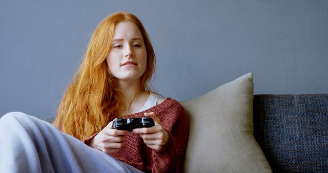 Young Woman with Red Hair Sitting on Couch Playing Video Games - Download Free Stock Images Pikwizard.com