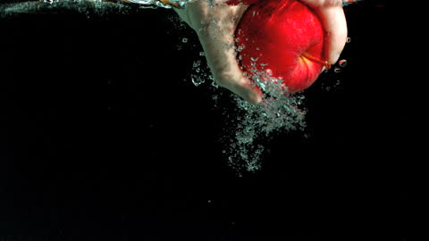 Person Grabbing Red Apple Under Water with Bubbles