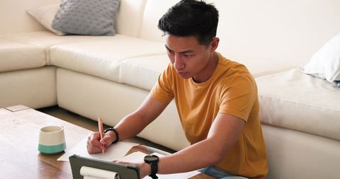 Young Professional Writing and Using Tablet in Minimalist Home Office