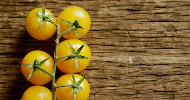 A branch of ripe yellow tomatoes rests against a rustic wooden background, with copy space - Download Free Stock Photos Pikwizard.com