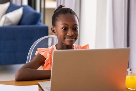 African american girl using laptop at home for remote learning and online study