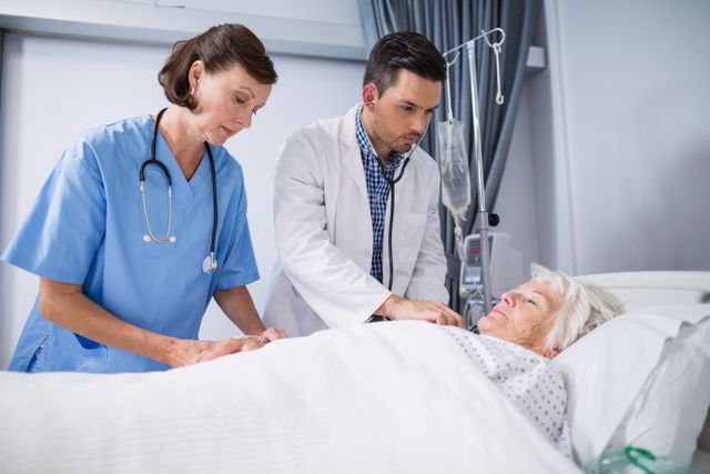Doctors and a nurse are examining a senior patient lying in a hospital bed. This image can be used for healthcare, medical care, elderly care, hospital services, and patient care themes. It is suitable for websites, brochures, and articles related to medical treatment and healthcare services.