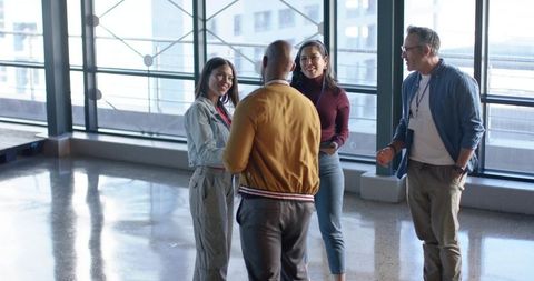 Diverse Coworkers Networking and Smiling in Modern Glass Atrium for Team Collaboration