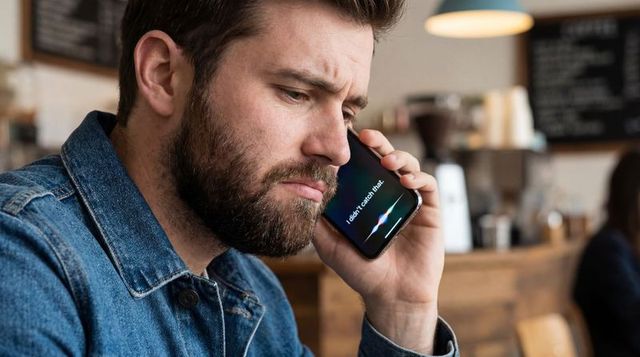 Bearded man using voice assistant on smartphone in cozy coffee shop