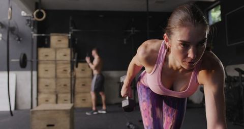 Focused Woman Performing Strength Training with Dumbbell in Modern Gym