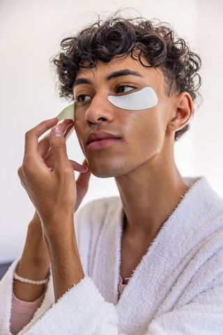 Young man applying hydrogel eye patches for skincare routine
