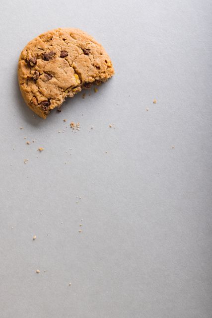 Half eaten cookie with crumbs on white background. Ideal for food blogs, dessert recipes, snack advertisements, minimalist designs, and healthy eating concepts.