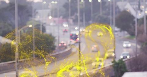 Curved urban highway descending at dusk, traffic flowing with glowing yellow light trails