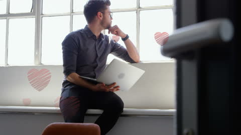 Man with Laptop Reflecting in Heart-Laden Atmosphere