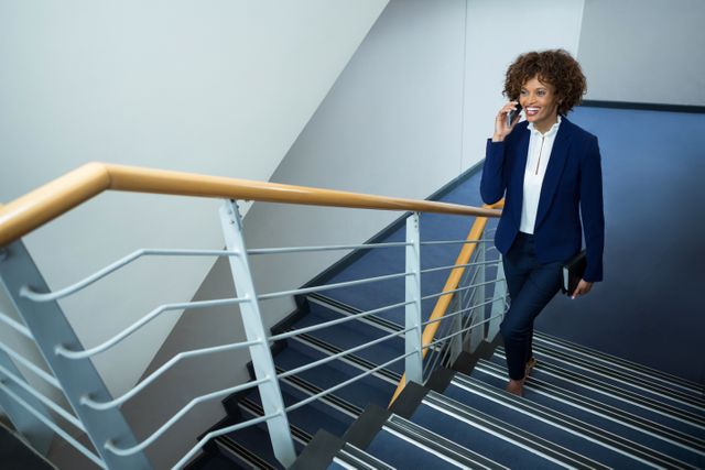 Businesswoman talking on mobile phone while climbing steps at conference centre
