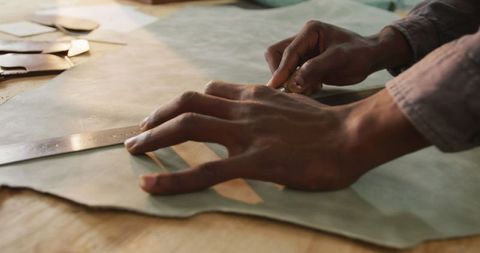 Hands of african american craftsman working with leather materials