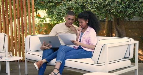 Diverse couple collaborating on patio in outdoor workspace