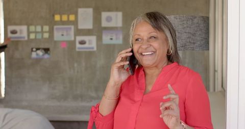 Senior Woman Smiling While Talking on Smartphone in Modern Office