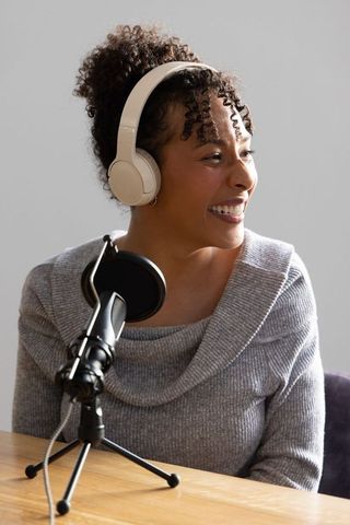 African american woman hosting podcast wearing headset and speaking into microphone