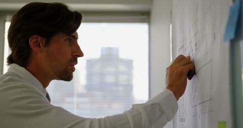 Caucasian Male Executive Working on Blueprint in Modern Office