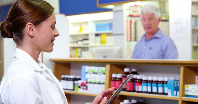 Pharmacist Using Tablet in Pharmacy with Colleague in Background - Download Free Stock Photos Pikwizard.com