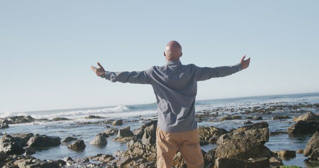 Man Embracing Nature with Open Arms Standing on Rocky Beach - Download Free Stock Images Pikwizard.com