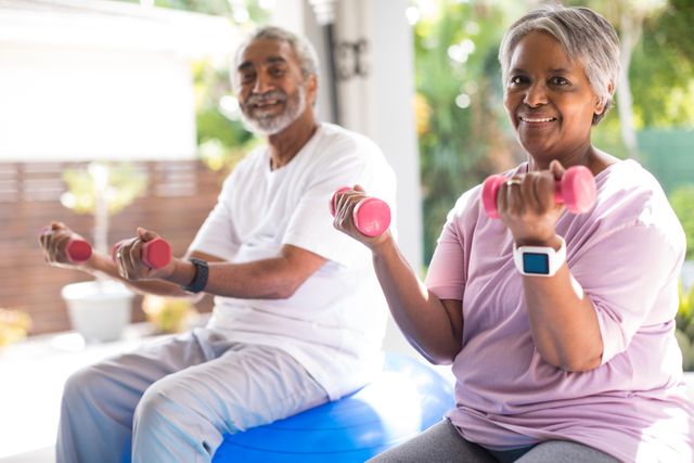 Senior couple lifting dumbbells outdoors, promoting healthy lifestyle and physical activity among elderly. Ideal for use in health and wellness campaigns, fitness programs for seniors, retirement community promotions, and articles on active aging.