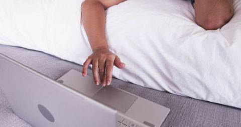 African american woman reaching for laptop from bed, remote work and morning routine