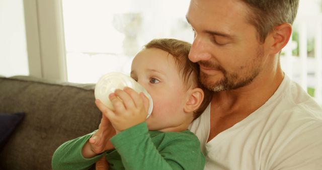 Father cuddling toddler who is drinking milk from bottle - Download Free Stock Images Pikwizard.com