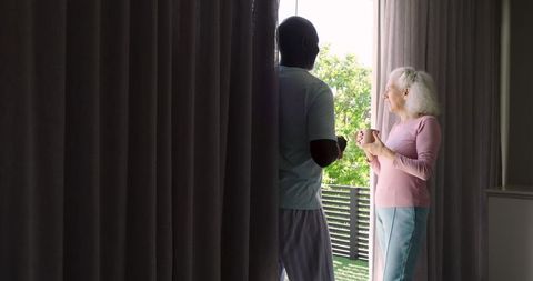 Diverse senior couple enjoying morning coffee by balcony