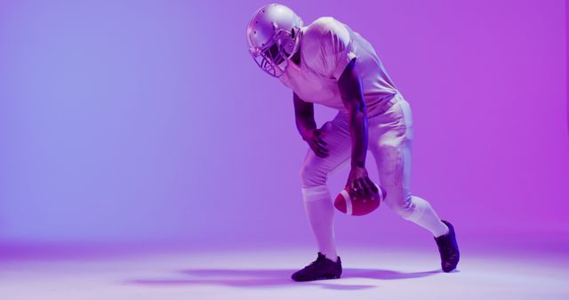 Image of african american american football player with ball over purple neon background. American football, sports and competition concept.